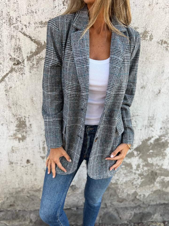 Swanet geruite blazer voor dames biedt warmte, comfort en tijdloze stijl. Gemaakt van een dikke katoen-polyestermix voor uitstekende isolatie tijdens koude dagen. Het klassieke geruite patroon en de getailleerde pasvorm zorgen voor een elegante look, ideaal voor zowel zakelijke als casual gelegenheden. Deze veelzijdige blazer combineert moeiteloos met elke outfit en is perfect voor het najaar en de winter. Een must-have voor een stijlvolle en verzorgde uitstraling.