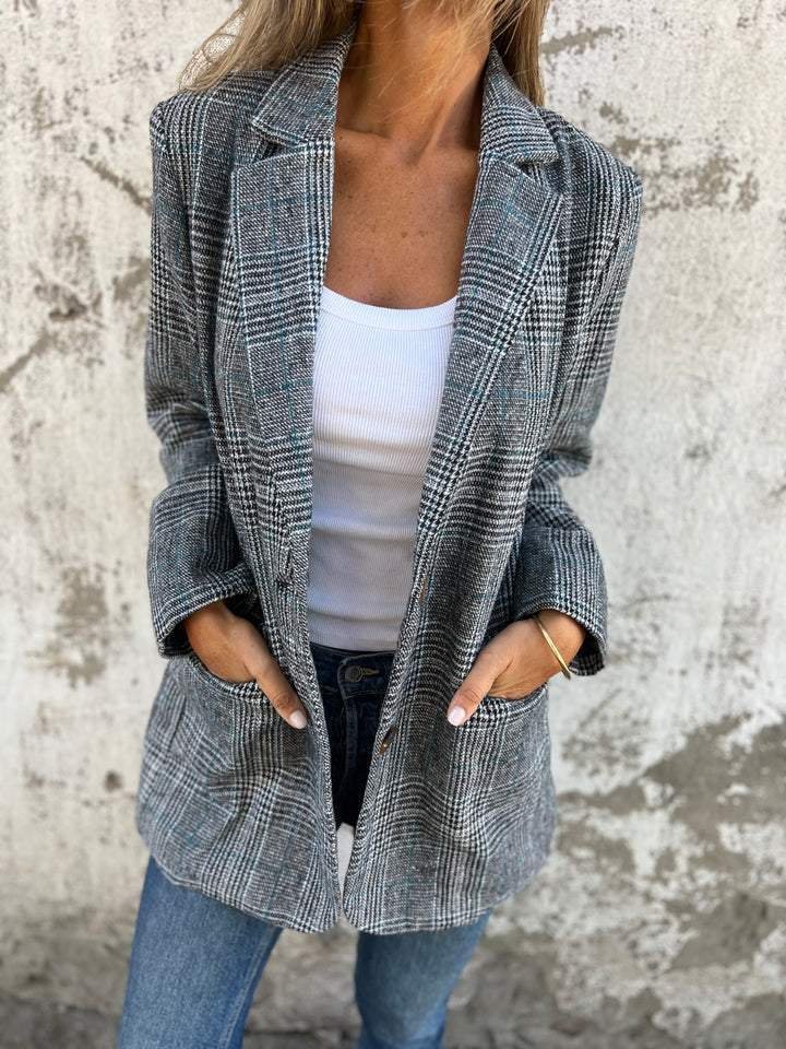 Swanet geruite blazer voor dames biedt warmte, comfort en tijdloze stijl. Gemaakt van een dikke katoen-polyestermix voor uitstekende isolatie tijdens koude dagen. Het klassieke geruite patroon en de getailleerde pasvorm zorgen voor een elegante look, ideaal voor zowel zakelijke als casual gelegenheden. Deze veelzijdige blazer combineert moeiteloos met elke outfit en is perfect voor het najaar en de winter. Een must-have voor een stijlvolle en verzorgde uitstraling.