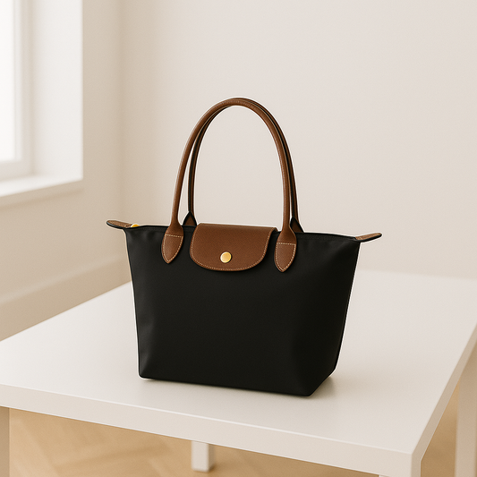Zwarte nylon schoudertas voor dames met bruine leren details, ruime binnenkant en goudkleurige sluiting – waterafstotende, stijlvolle tas voor werk, reizen of dagelijks gebruik.
