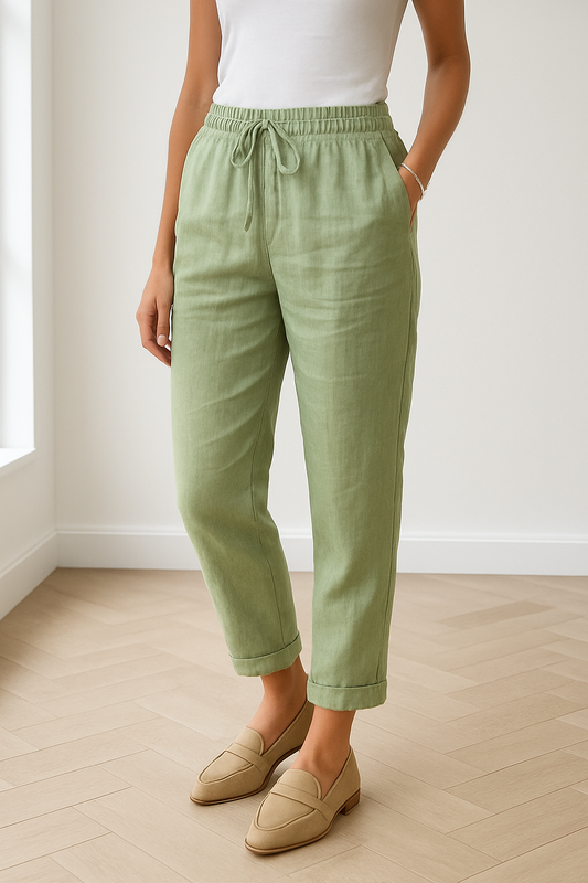Lichtgroene linnen broek voor dames, gedragen in een lichte moderne kamer met beige loafers.