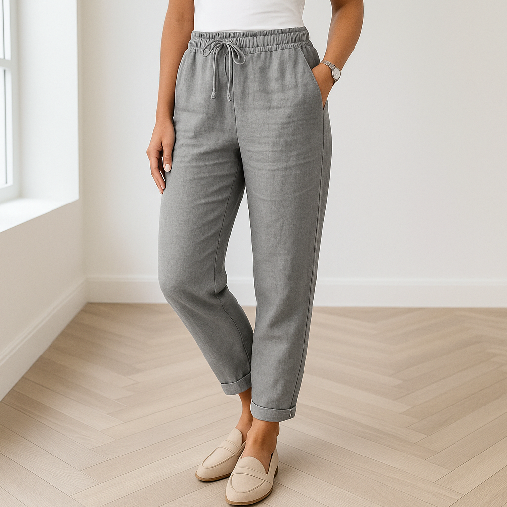 Grijze linnen broek voor dames, gecombineerd met neutrale loafers in een moderne ruimte met houten vloer.