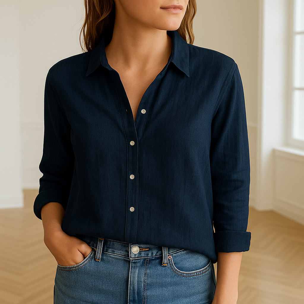 Linnen damesblouse met lange mouwen en knoopsluiting, gedragen door een vrouw in een lichte, moderne kamer met houten visgraatvloer. De blouse heeft een klassieke kraag en is gemaakt van luchtige, ademende stof voor een stijlvolle en comfortabele uitstraling.