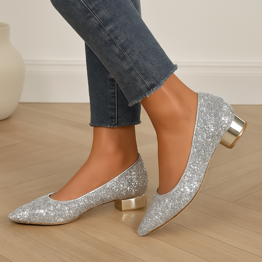 Zilverkleurige glitterballerina's voor dames met een chroomkleurige hak en spitse neus, gedragen met een denim jeans. Perfect voor feestelijke of chique gelegenheden.